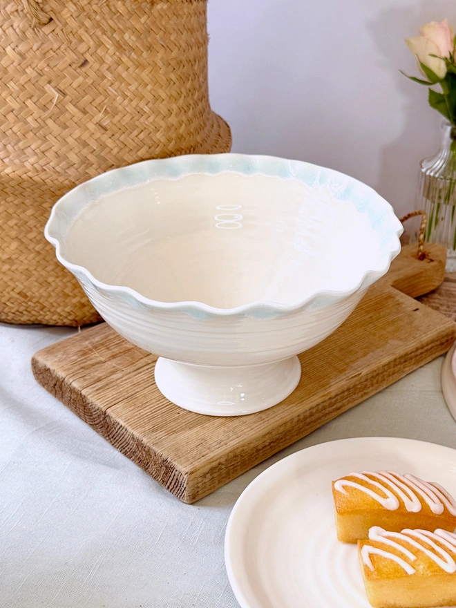 undulating rim hand thrown stem bowl with turquoise blue edge on rustic table