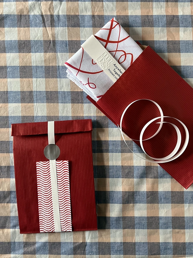 Optional gift wrap of red paper and wavy printed gift card on a gingham tablecloth