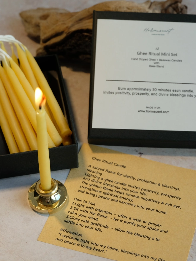 Burning mini ghee candle used for cleansing, prayer and intention-setting, shown with a box of handmade ritual candles and an affirmation card.