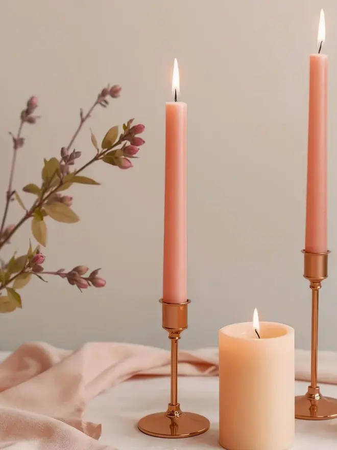 Coral dinner candles in a brass candle holder on a table