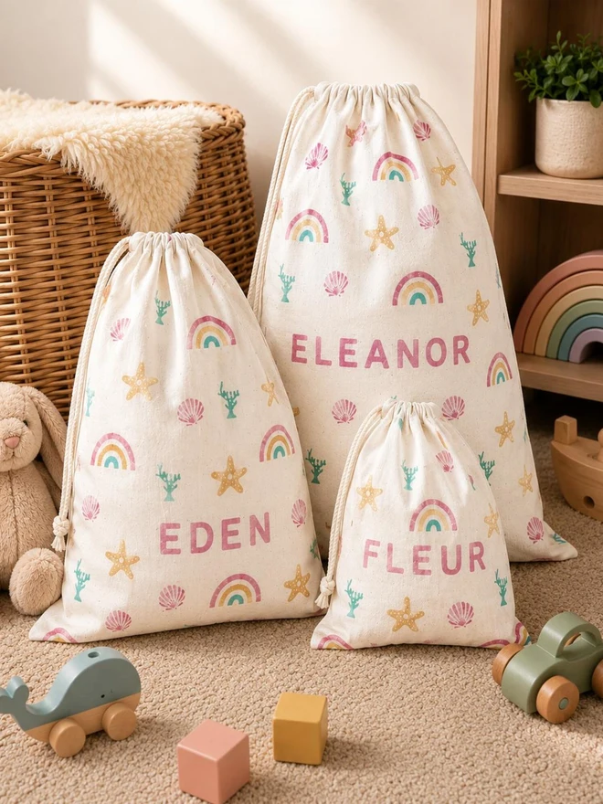 personalised toy sack. three drawstring bags with printed rainbows and personalised names.