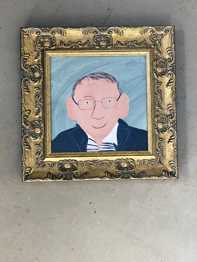 framed painting of a man with blue jacket and glasses