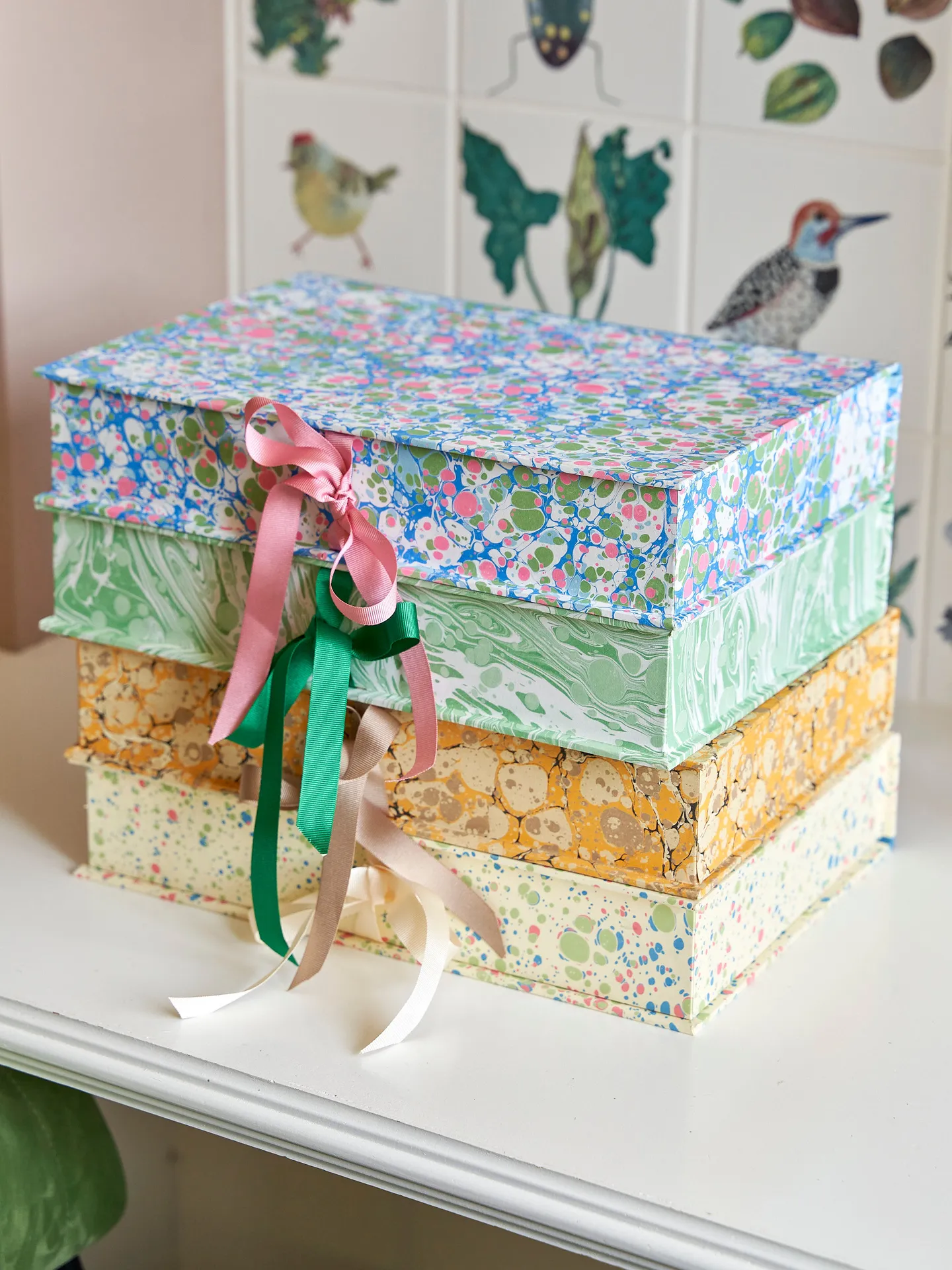 stack of four keepsake boxes. each box is hand marbled in a different pattern/colour and has a ribbon tie closure