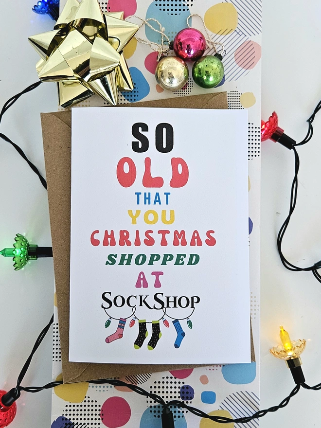 A photograph of the front of a humorous A6 greeting card illustrated using brightly coloured text and the retro shop logo. The text says so old you Christmas shopped at Sock Shop
