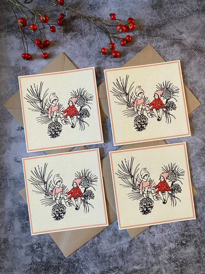 4 Christmas cards featuring 2 children holding hands on a pinecone branch