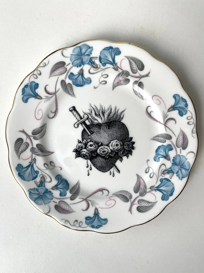 a vintage plate with an ornate border and in the centre is an old illustration of a beautiful sacred heart