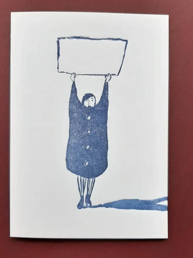 Blank Message Letterpress Handprinted Blue Greetings Card, a white card with a blue design sitting above a dark red background.