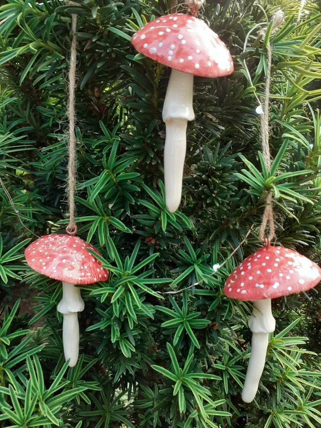 Handmade ceramic red toadstool Christmas ornaments hanging on tree