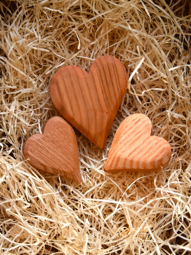 Set of three red wooden hearts lying in woodwool