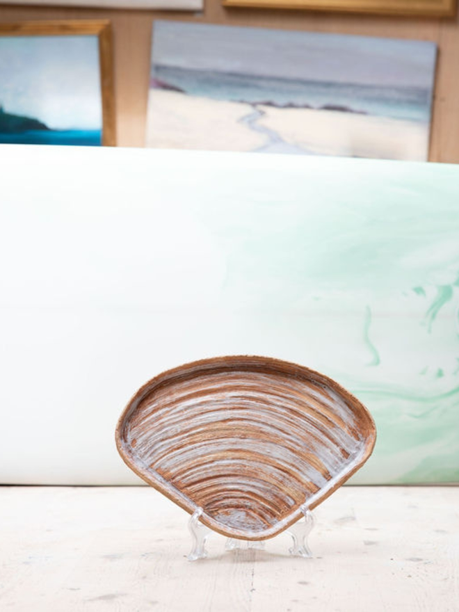 8. Striped Venus Clam Ceramic Plate on a stand in a neutral toned room