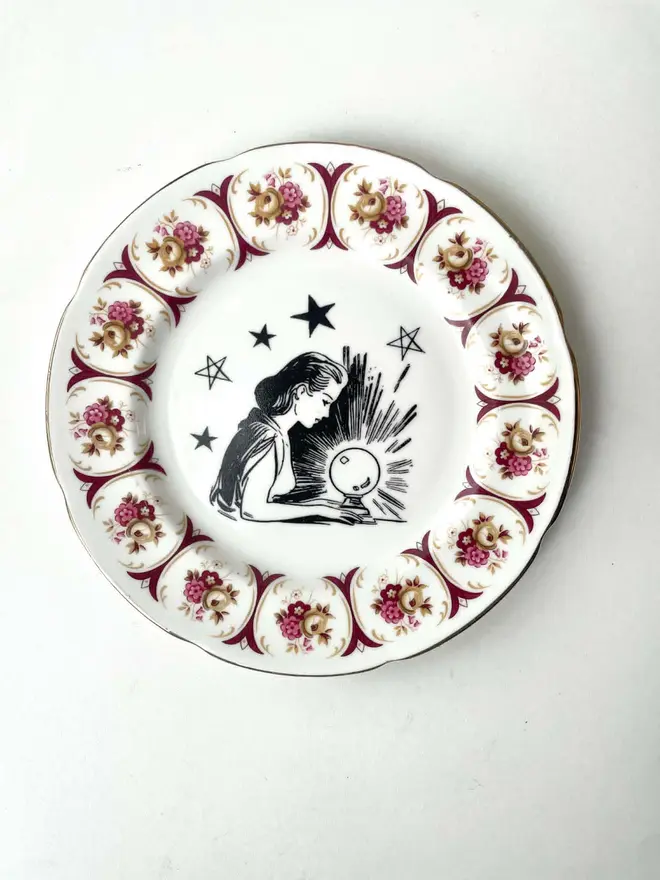 a vintage ornate plate with a pink floral border detail, in the centre i have printed a vintage black and white illustration of a pretty fortune teller reading a crystal ball