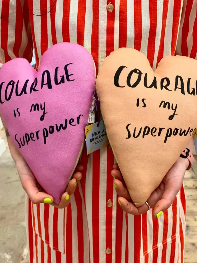 Courage heart plushie seen held by someone wearing a red striped dress