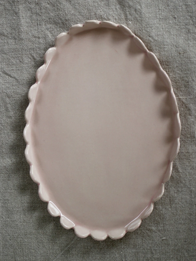 top view of oval pale pink plate with upright scalloped edges s