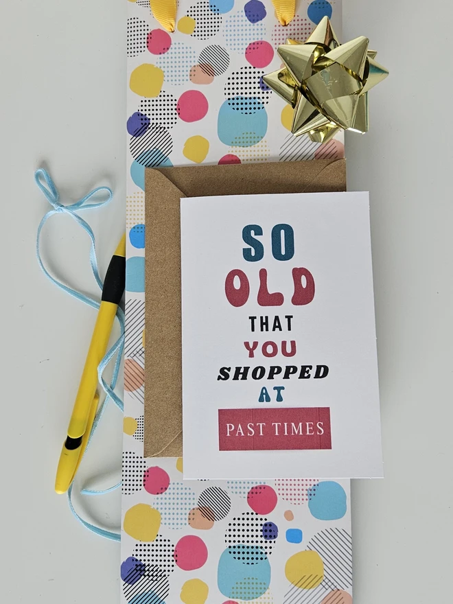 A photograph of the front of a humorous A6 greeting card illustrated using brightly coloured text and the retro shop logo. The text says so old you shopped at Past Times