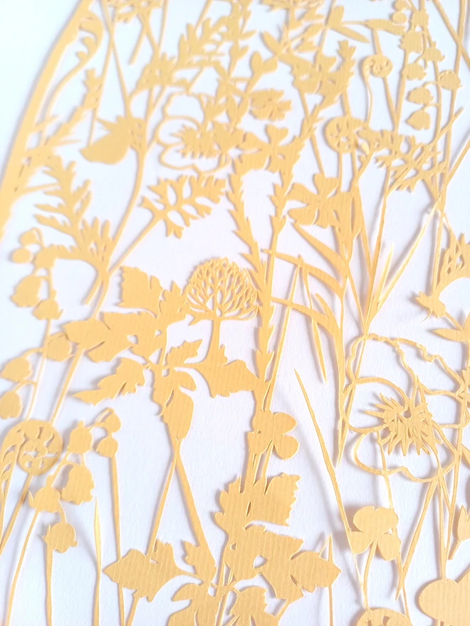 Closeup up view of pale yellow papercut including spring flowers and leaves
