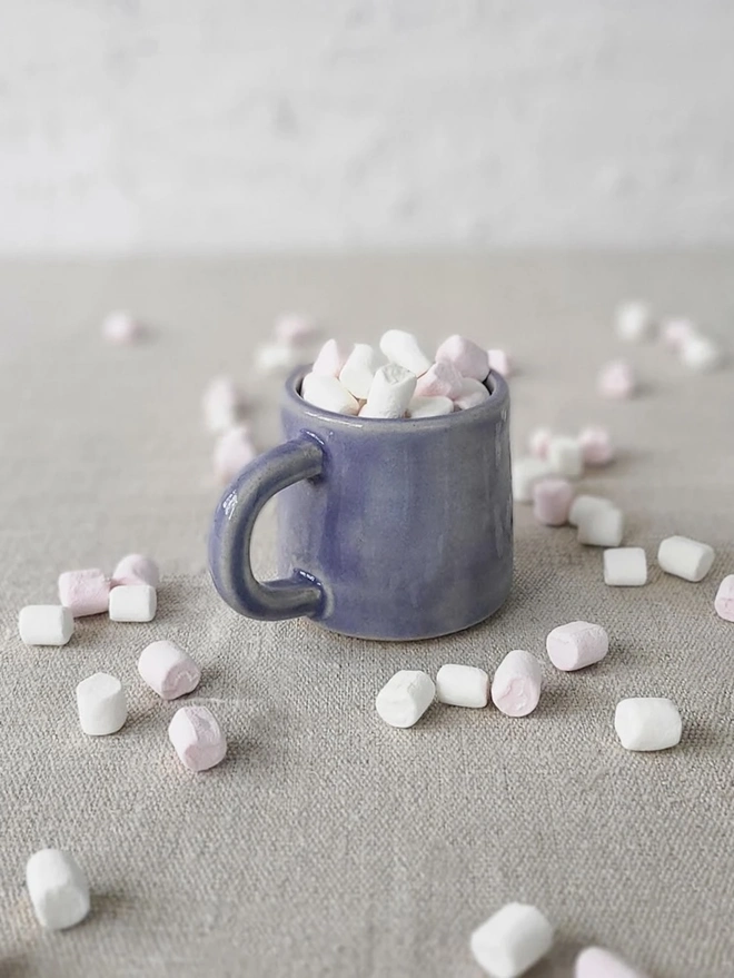 Classic Ceramic Espresso Mug, a colourful ceramic espresso mug sitting on a plain surface against a white backdrop. It is accompanied by a group of marshmallows. 