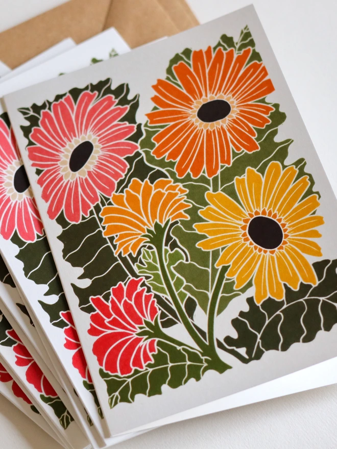 Close-up of Joy Bloom Gerbera Daisy notecard designs from hand-carved botanical set. Linocut print stationery showing bright and colourful daisy flowers. Bold contemporary colours on A6 recycled cards. Norfolk studio, no AI