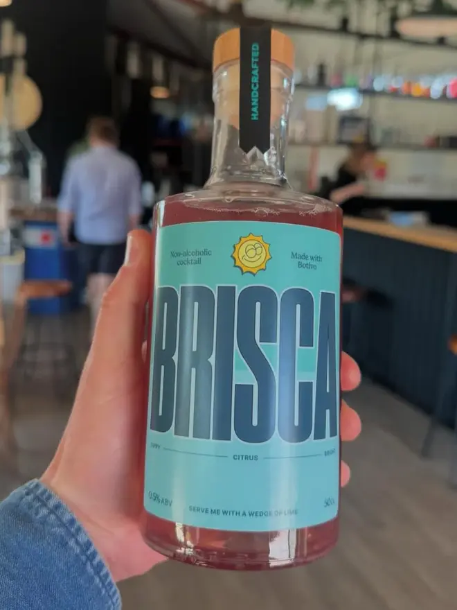 Brisca Non Alcoholic Cocktail, bottle of cocktail held by a hand. 