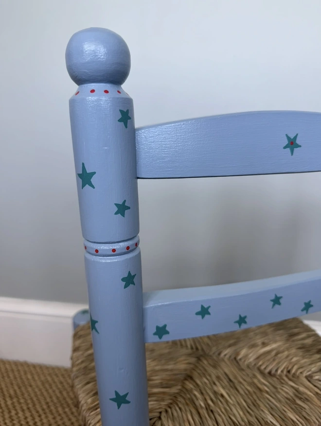 Christening chair painted in blue with green starts and red dot details. 