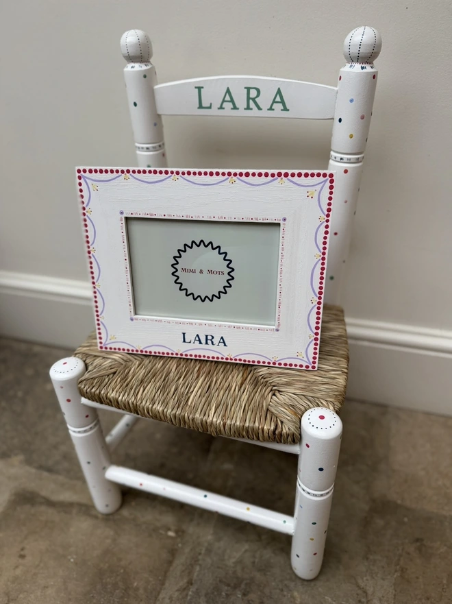 Personalised with the name Lara in green and a photo frame sitting on the chair. 