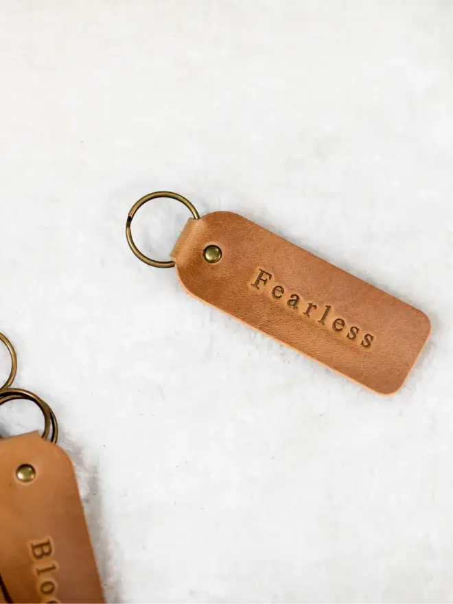 custom leather embossed keyring. a light brown leather keyring embossed with 'fearless' photographed against a white background.
