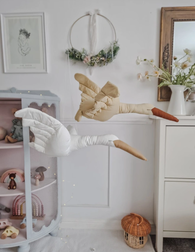 Flying Swan Hanging Decoration, a hanging beige swan decoration, suspended in a child's bedroom. 