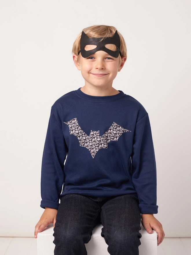 a 5 year old boy wearing a navy cotton t-shirt with a monochrome Liberty fabric bat sewn on the front.