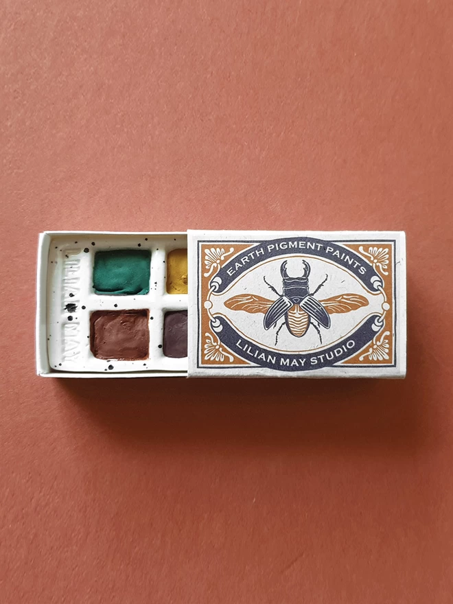 An open matchbox paint set with a stag beetle design.