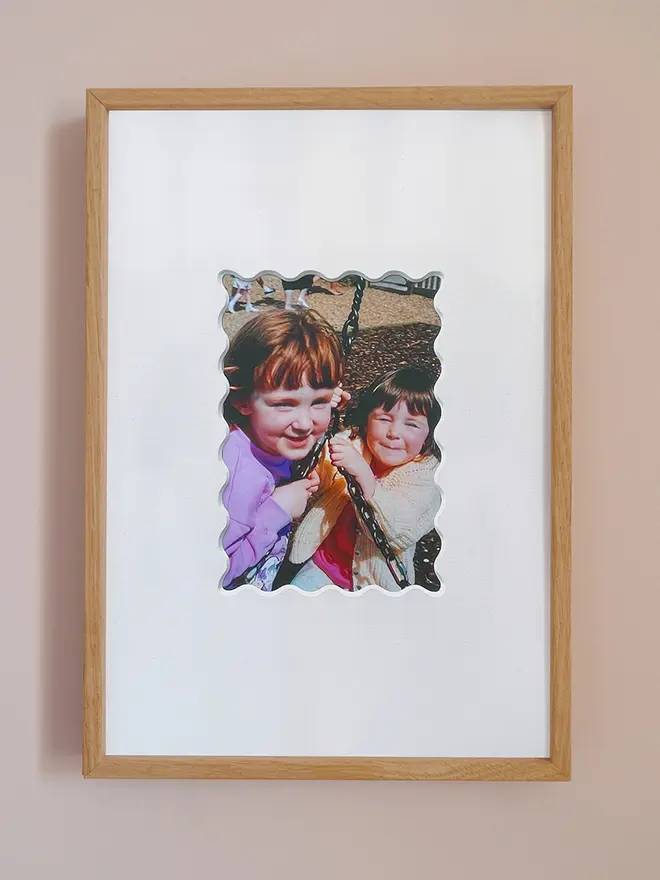 Ric rac photo mount frame with a white mount featuring a decorative ric rac boarder around a centered photo, displayed on a neutral beige wall.