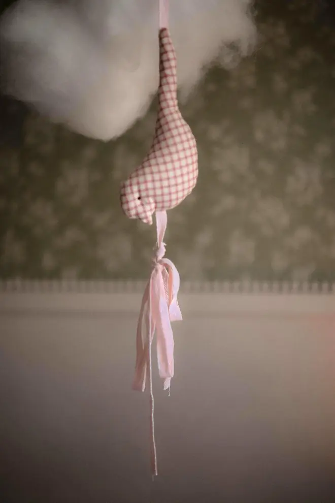 Cotton Bird Garland Decoration, a suspended red and white cotton bird garland hanging in a child's bedroom. 