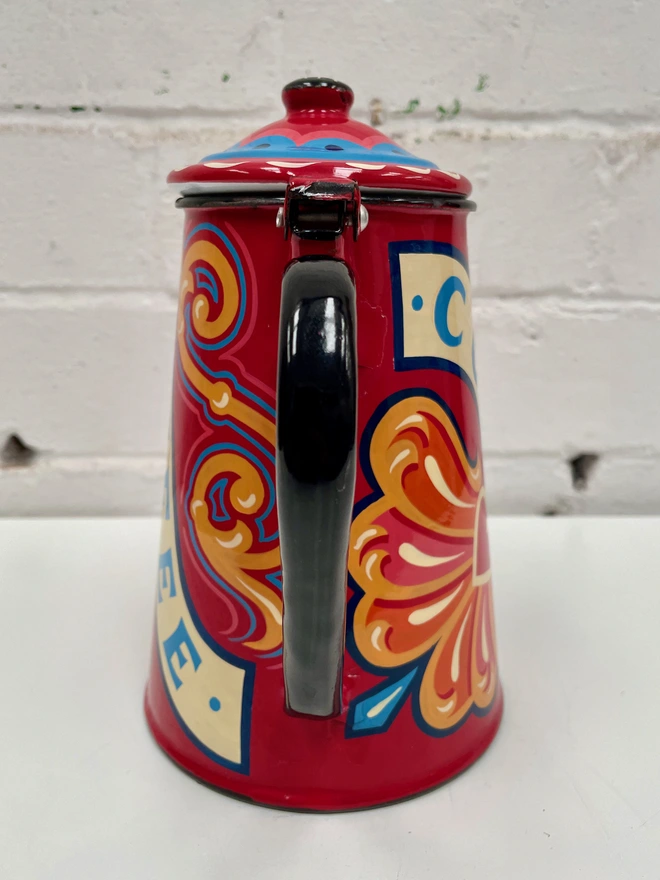 Red vintage coffee pot, hand painted with a fairground inspired design in pink, orange and yellow. 'Coffee' is painted in a banner through the centre of the design.