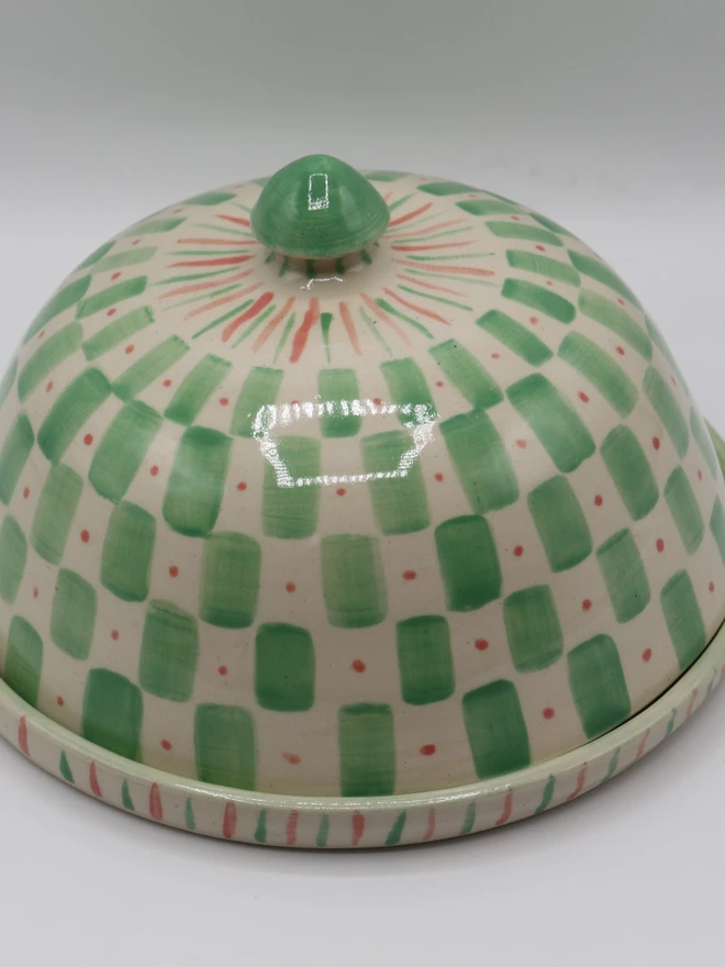 Domed ceramic butter dish that has been made on the pottery wheel and then hand painted in a green checkered pattern