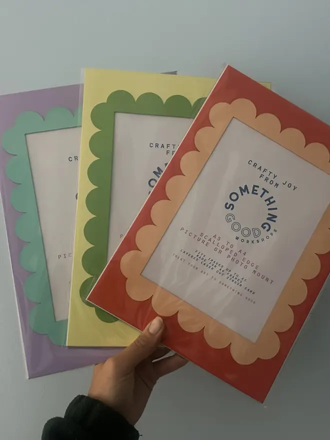 Scallop Edged A5 / A4 photo mount. green and yellow, purple and blue and red and orange variants held against grey background. 