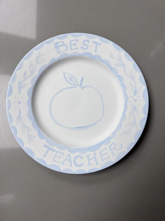 Blue and white Thank You Teacher Plate awaiting personalization. Best Teacher around the rim with outline of an apple inset