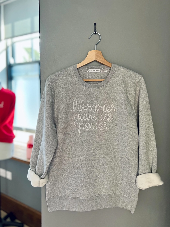 A grey sweatshirt on a hanger embroidered with libraries gave us power
