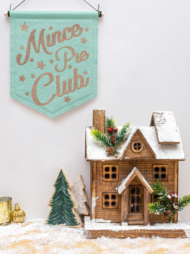 Christmas "Mince Pie Club" banner in pale mint felt with champagne gold glitter text. the text is surrounded by glittery stars.. 