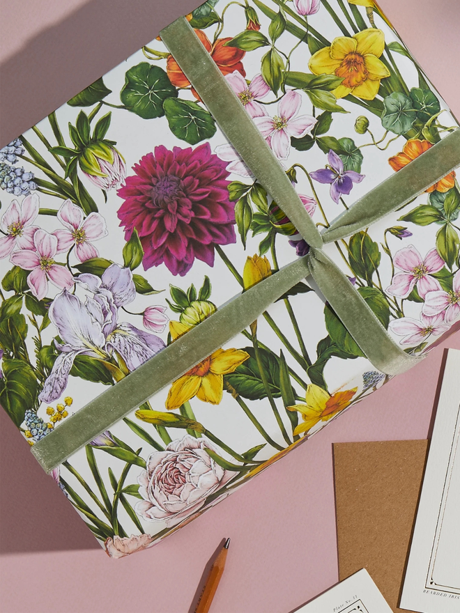 bountiful blooms floral gift wrap sheet. a box wrapped in multi-coloured illustrated floral gift wrap with a green ribbon.