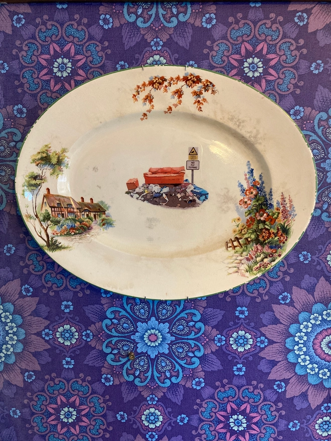 large oval vintage plate featuring a cottage on the left with a floral border. In the centre sits a pile of rubbish with an old sofa on top, next to a sign stating 'no fly tipping'.