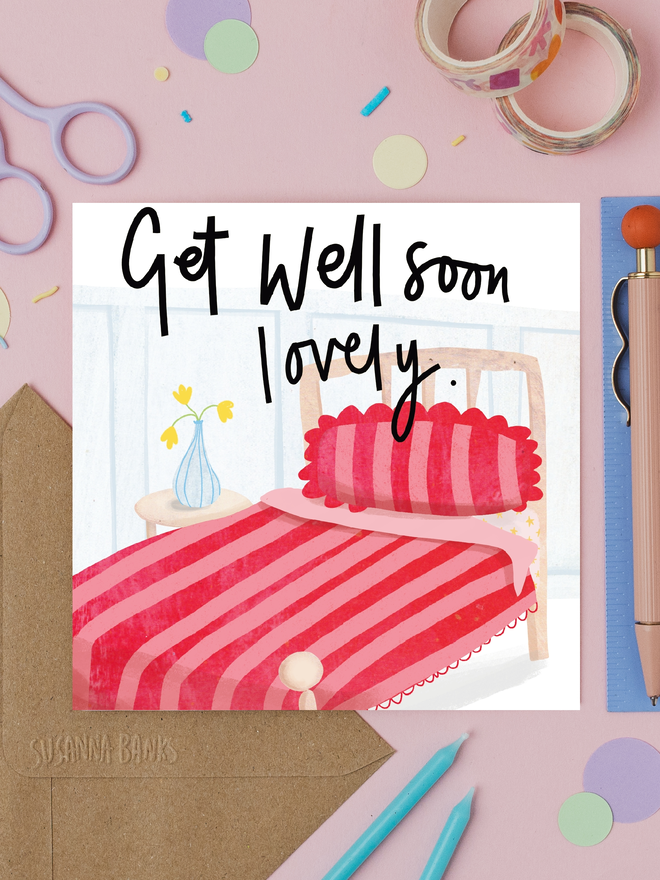 'get well soon lovely' illustrated card. card photographed on table with various craft items.