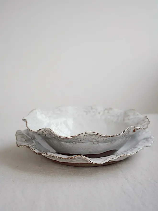 Dapple Stoneware Cereal & Salad Bowl, stacked with another ceramic, placed on a table cloth. 