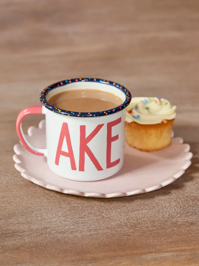 white mug with pink 'cake' text and paint splatter rim