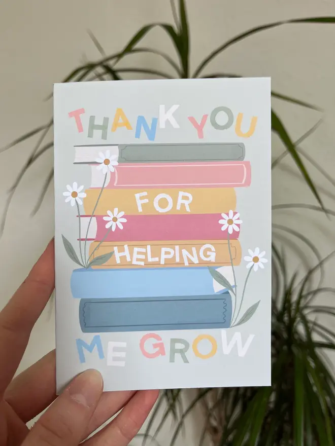 'thank you for helping me grow' illustrated card. green card with illustrated books and flowers.
