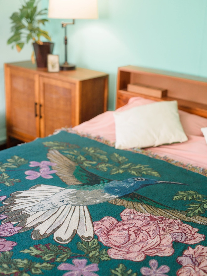 Joy Hummingbird Woven Blanket on bed