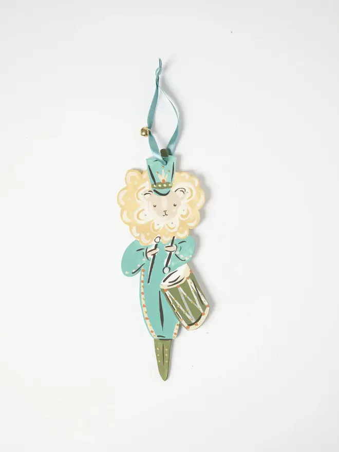 Lion Drummer Tree Dancer. wooden hanging lion drummer decoration with a duck egg blue tunic, cream mane and olive green drum, blue ribbon with a jingle bell, on a white background