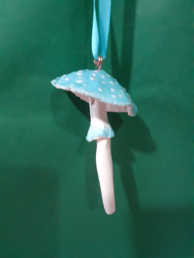 Handmade ceramic blue toadstool hanging decoration with white polka dots and a matching blue satin ribbon.