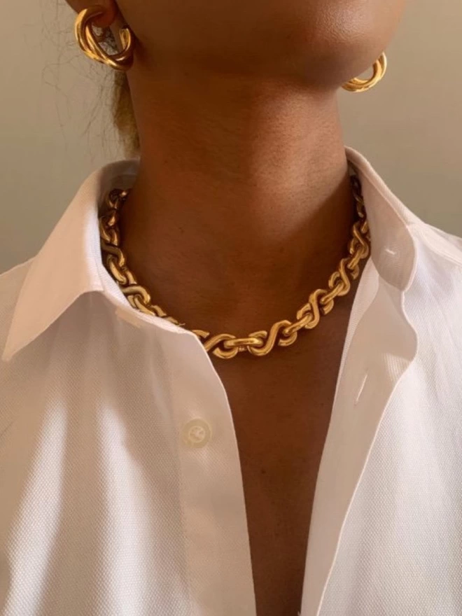a stunning handcrafted heavy weight gold collar worn with a simple crisp white shirt