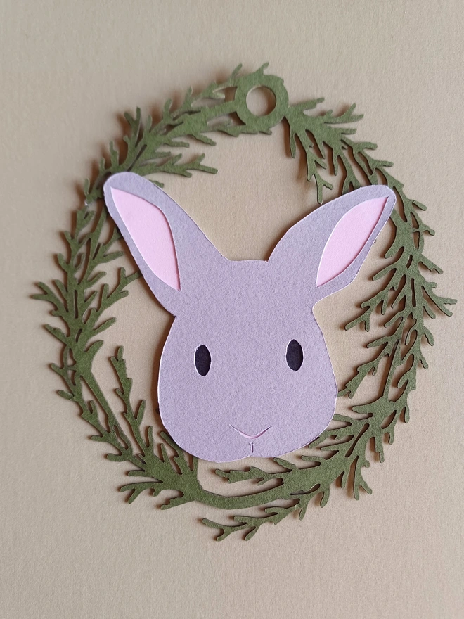 Black Bunny Easter Tree Decoration. Pale grey bunny face with black eyes and pale pink ears inside olive green foliage wreath oval