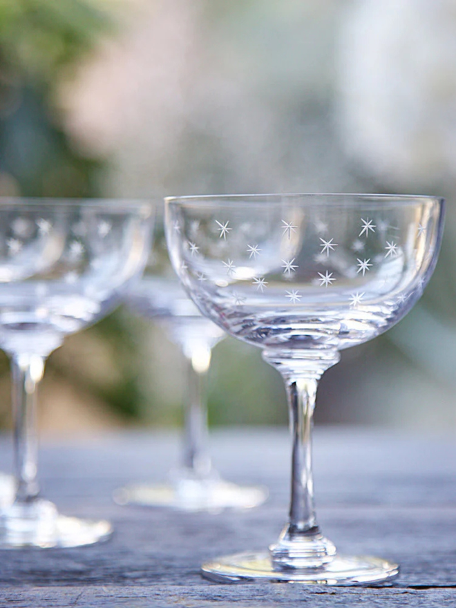 engraved stars crystal champagne saucers. a coupe champagne glass patterned with small stars.
