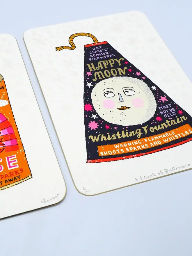 A Flash Of Brilliance Moon Firework Screenprint, a colourful firework design in the centre of a white screenprint. It is placed on a baby blue surface. 