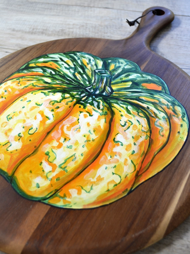 Wooden serving board with a handpainted design of a carnival squash